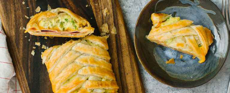 Breakfast Braid on a wooden cutting board next to a bowl