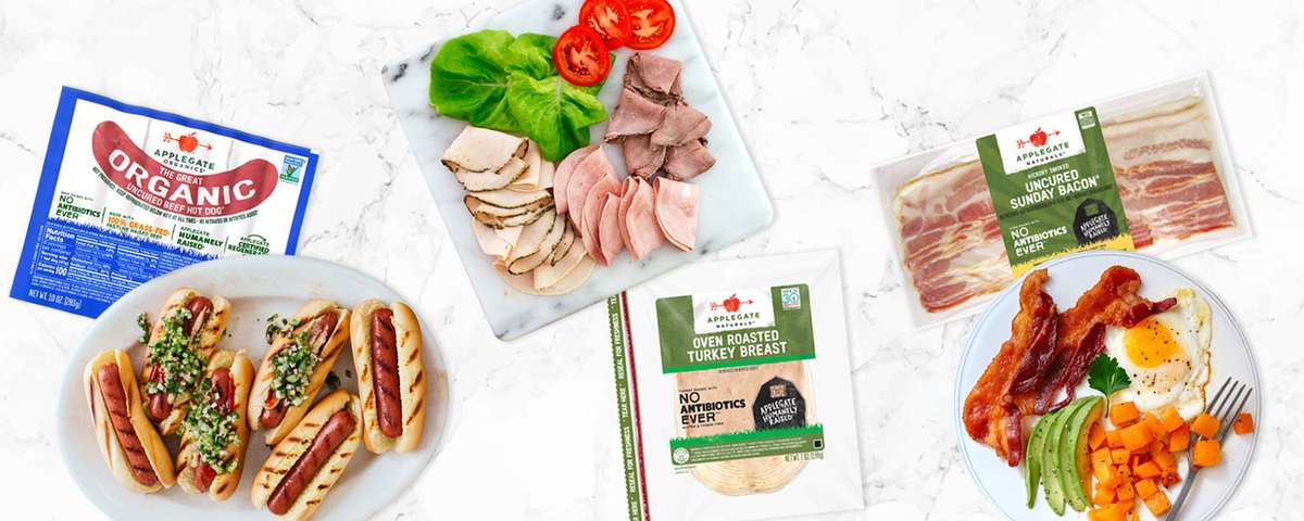 Applegate packaged products on a marble counter top with plates of tasty, prepared dishes.