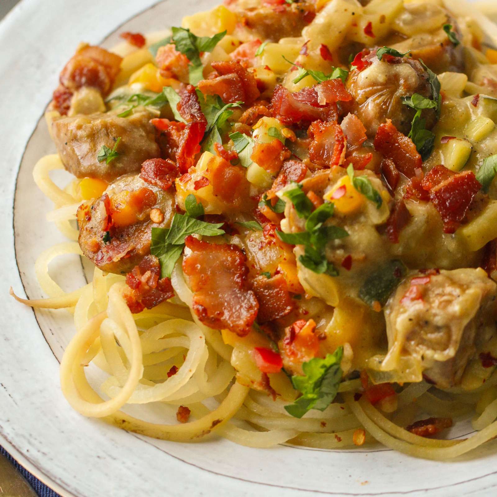 A colorful dish of the Whole30 Bacon Chicken Sausage Skillet with bacon, sausage, veggies and noodles